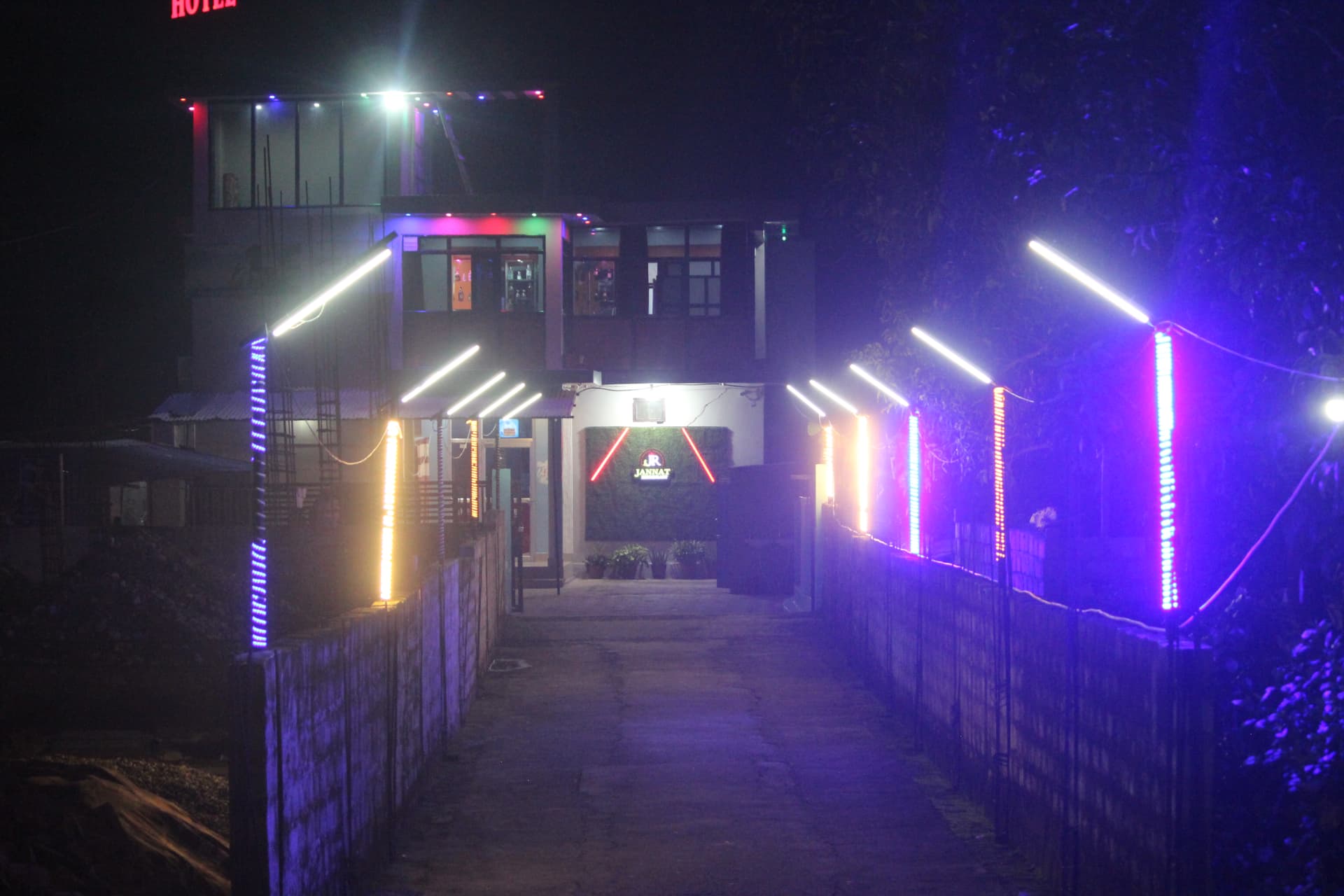 Jannat Restaurant & Lodge lit up at night from the entrance path